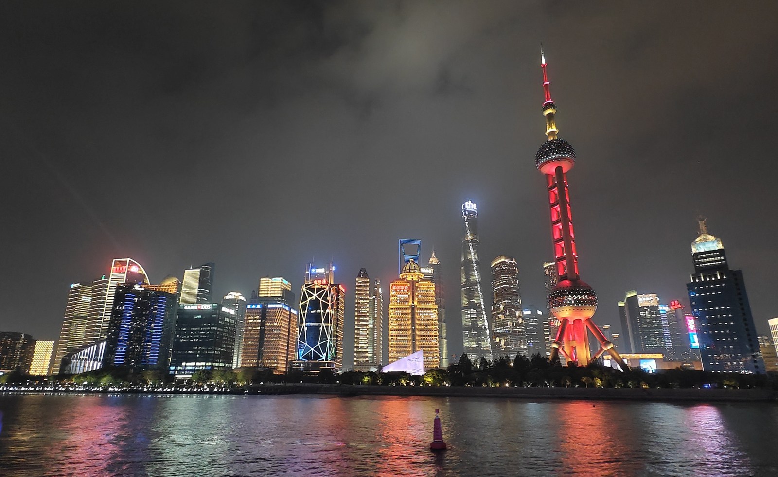 Sanghaj · Pudong kivilágított felhőkarcolói a Huangpu folyóról